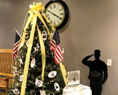 evergreen tree with yellow ribbons and American flags and ornaments featuring names and photos of service members