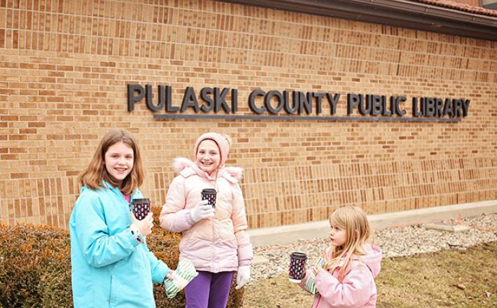 girls drinking cocoa in front of the Pulaski County Public Library building